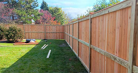 A backyard with a wooden fence in the process of being installed by Francisco Fence Company