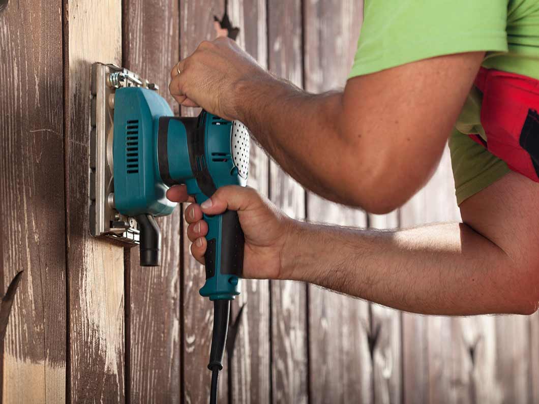 Fence repair of a worn wooden fence, using a sander