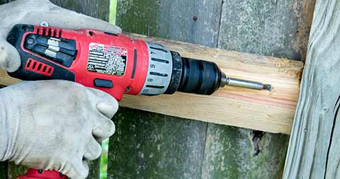 A drill being used in wooden fence repair